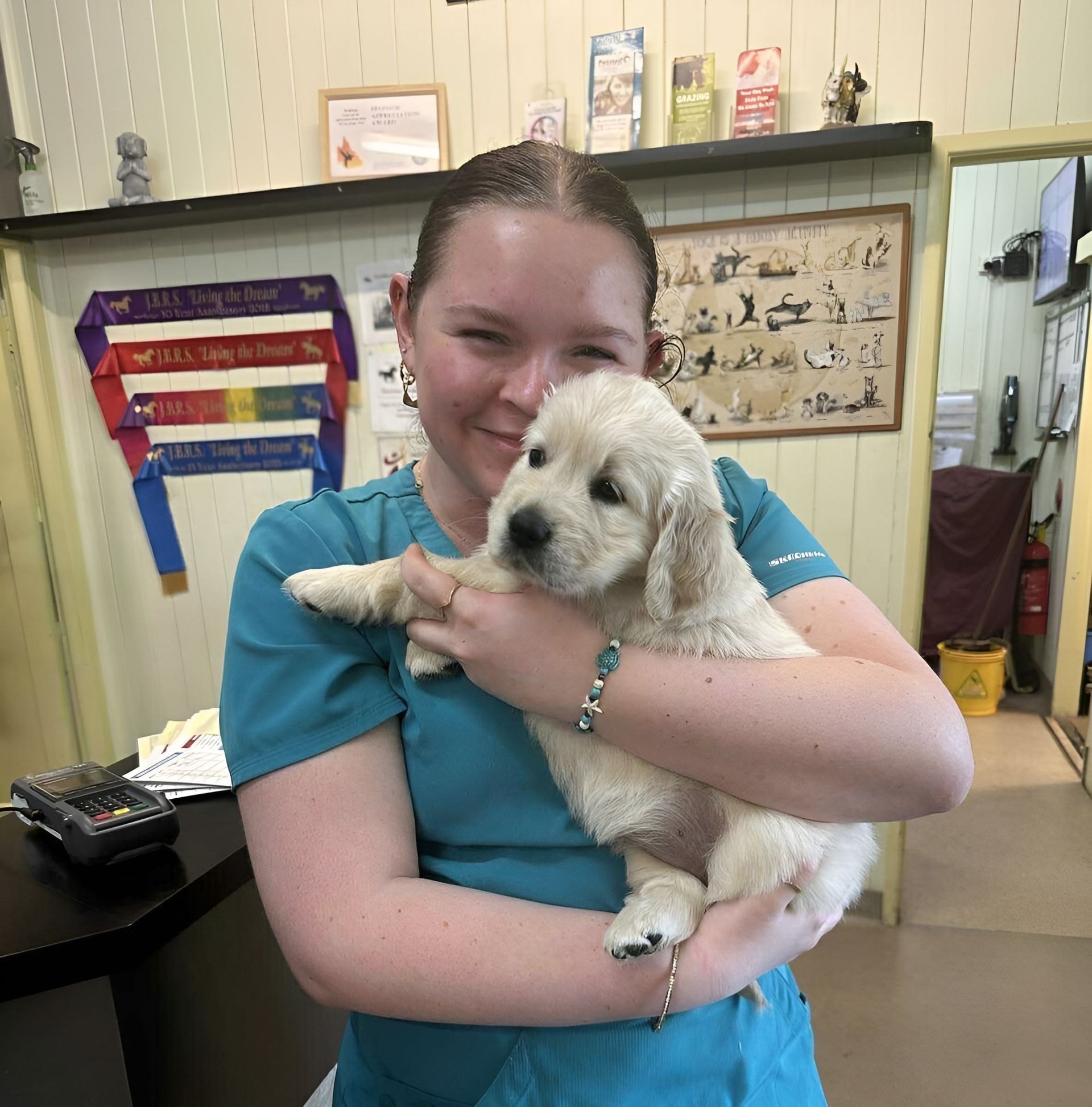 Woman in A Teal Shirt Holding a Fluffy White Puppy Indoors — Sarina Veterinary Surgery In Sarina, QLD