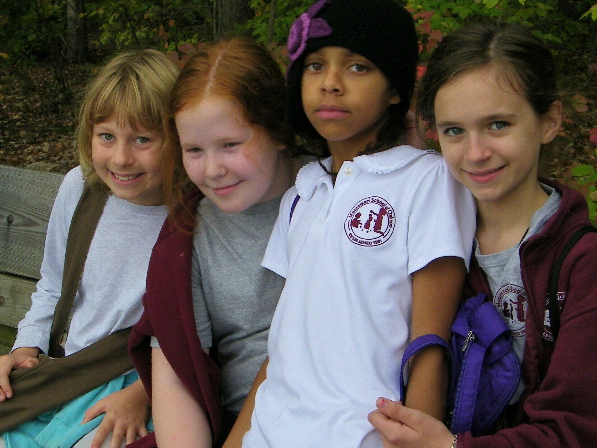 A gorup of children smiling to the camara wearing the Montessori School of Oakton uniforms
