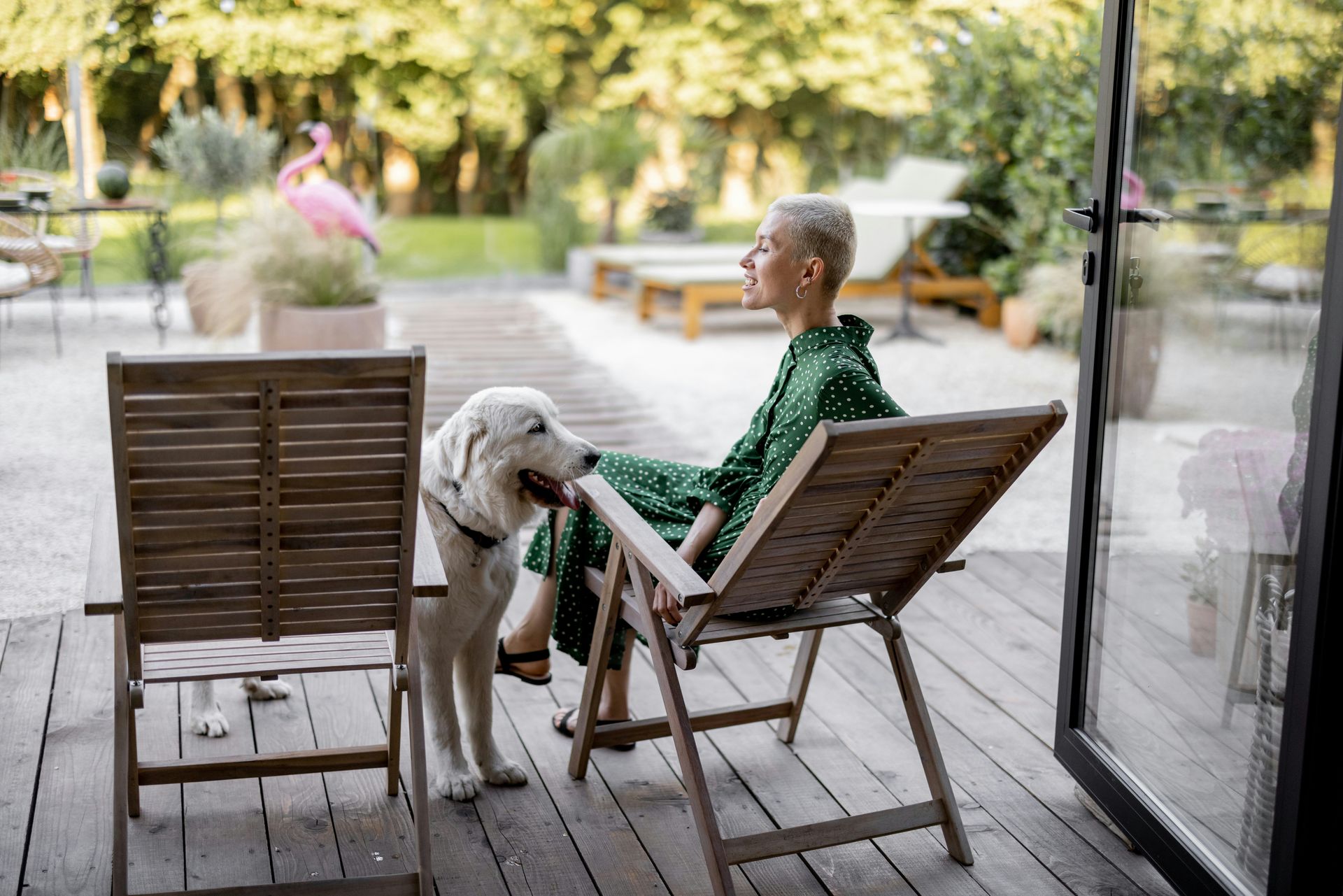 A woman is sitting in a chair on a deck with a dog.