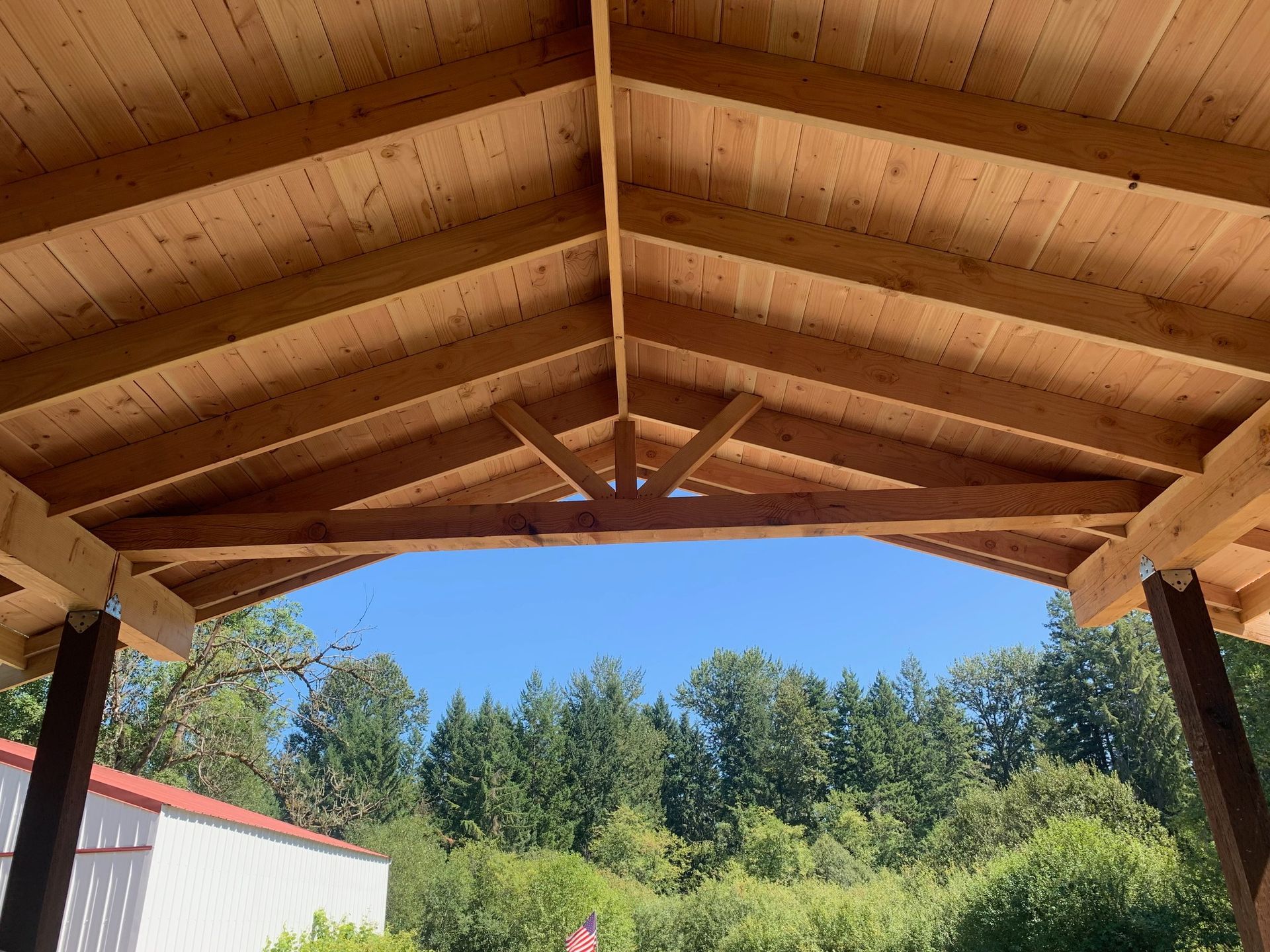 The roof of a wooden structure with trees in the background