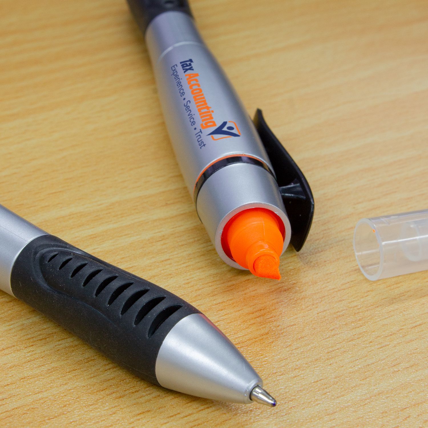 Silver and black pen with an orange highlighter tip, a black clip, and clear cap laying on a wooden surface.
