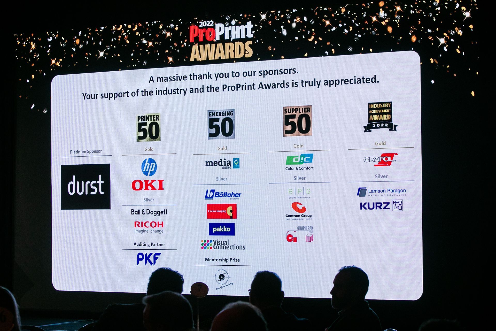 A screen displays ProPrint Awards sponsors' logos. Audience silhouettes are in the foreground.