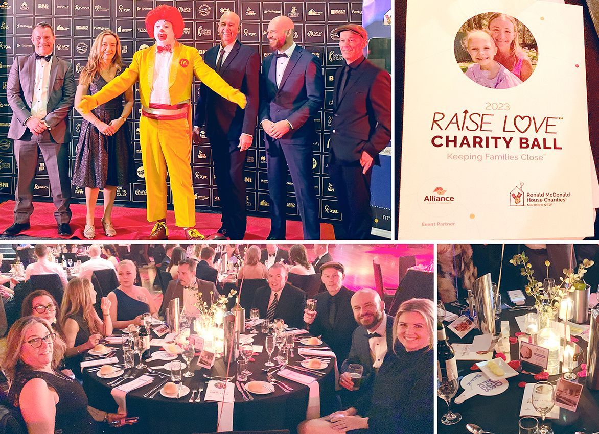 A charity ball with a group of formally dressed people, including Ronald McDonald, with event signage and table settings.