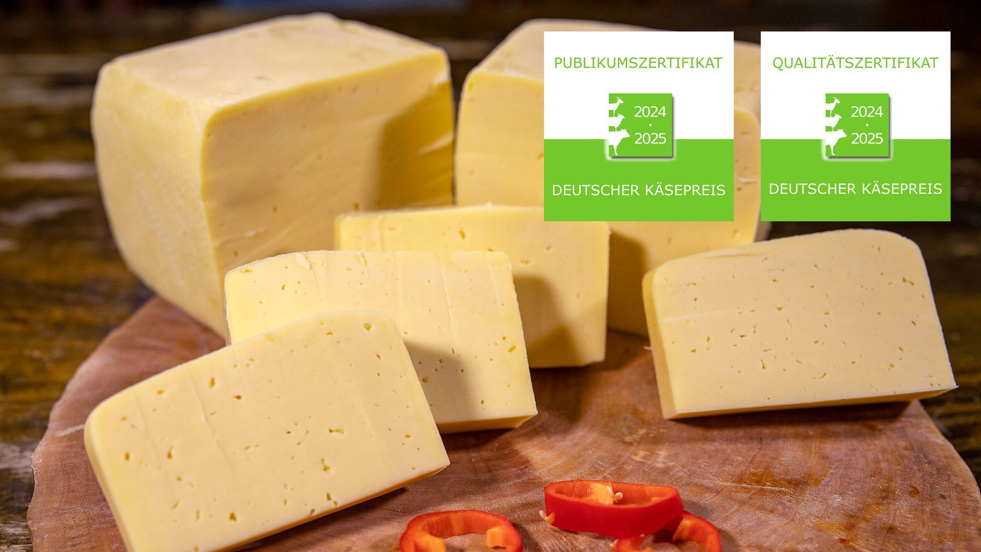 Ein hölzernes Schneidebrett mit mehreren Stücken Heidekäse und Paprika. Zwei Logos vom Deutschen Käsepreis 2024-2025.