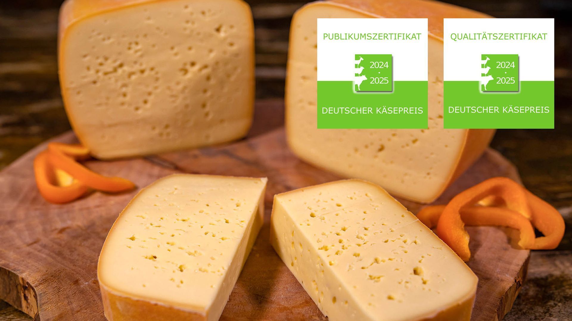 Vier Stückr Papenburger Abendrot auf hölzernen Schneidebrett. Daneben orangene Paprika. Mit Logo für Deutschen Käsepreis.