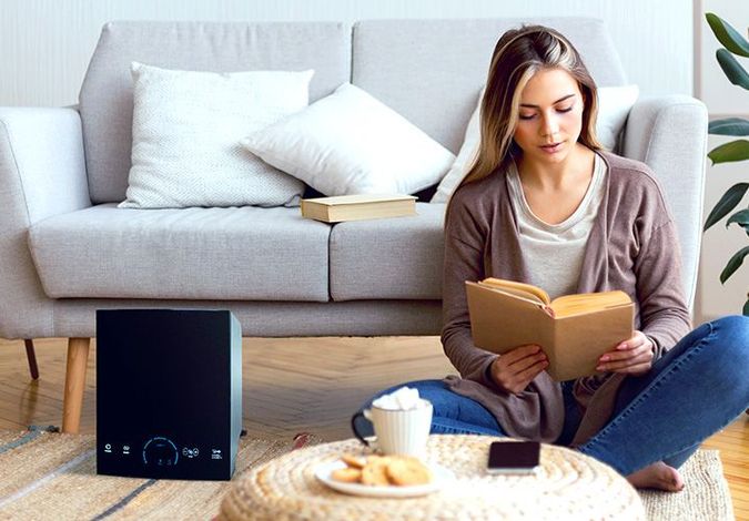 Woman reading a book on the floor beside a sofa, with a coffee cup and snacks nearby