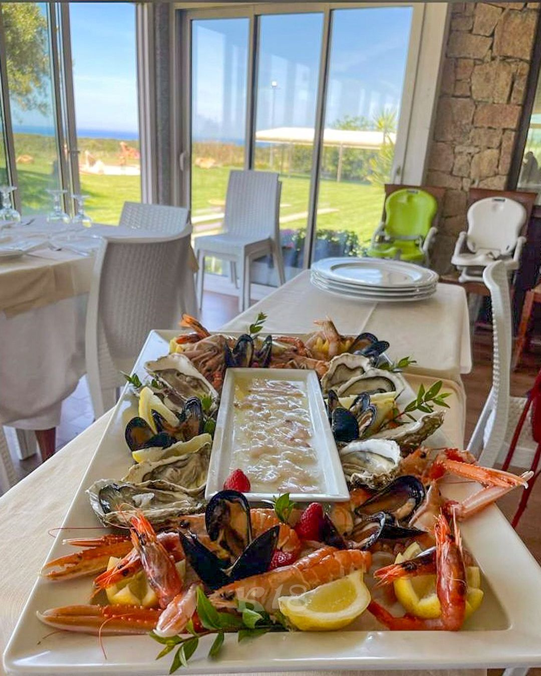 Piatto di frutti di mare con ostriche e aragosta su un tavolo in un luminoso ristorante sul mare.