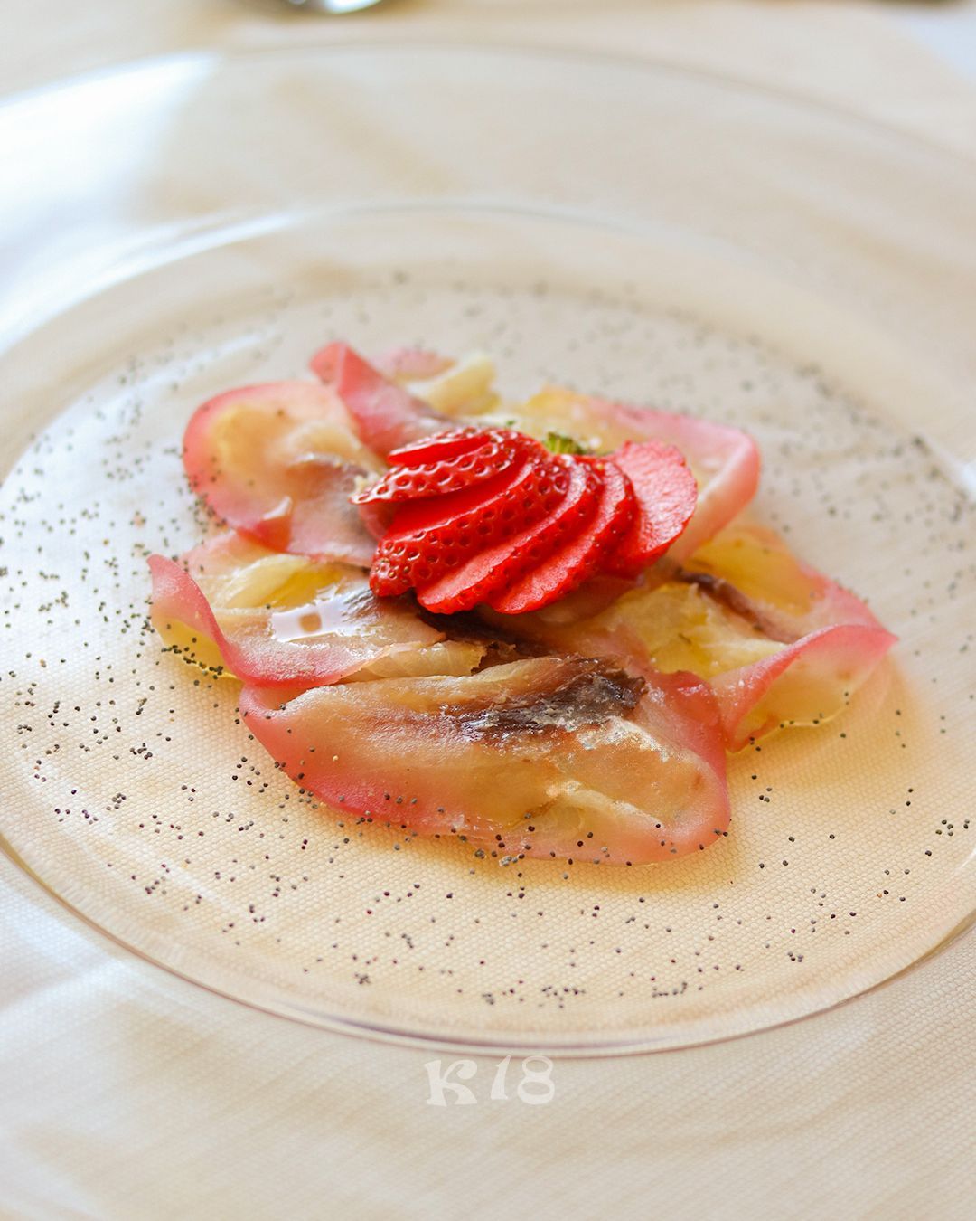 Elegante dessert su un piatto bianco, guarnito con fragole a fette e una salsa leggera.