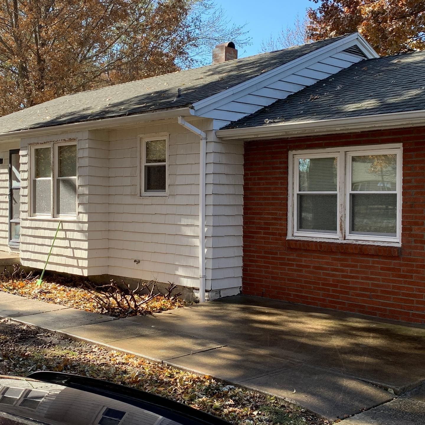House with white siding and red brick exterior, set in front of a sidewalk.