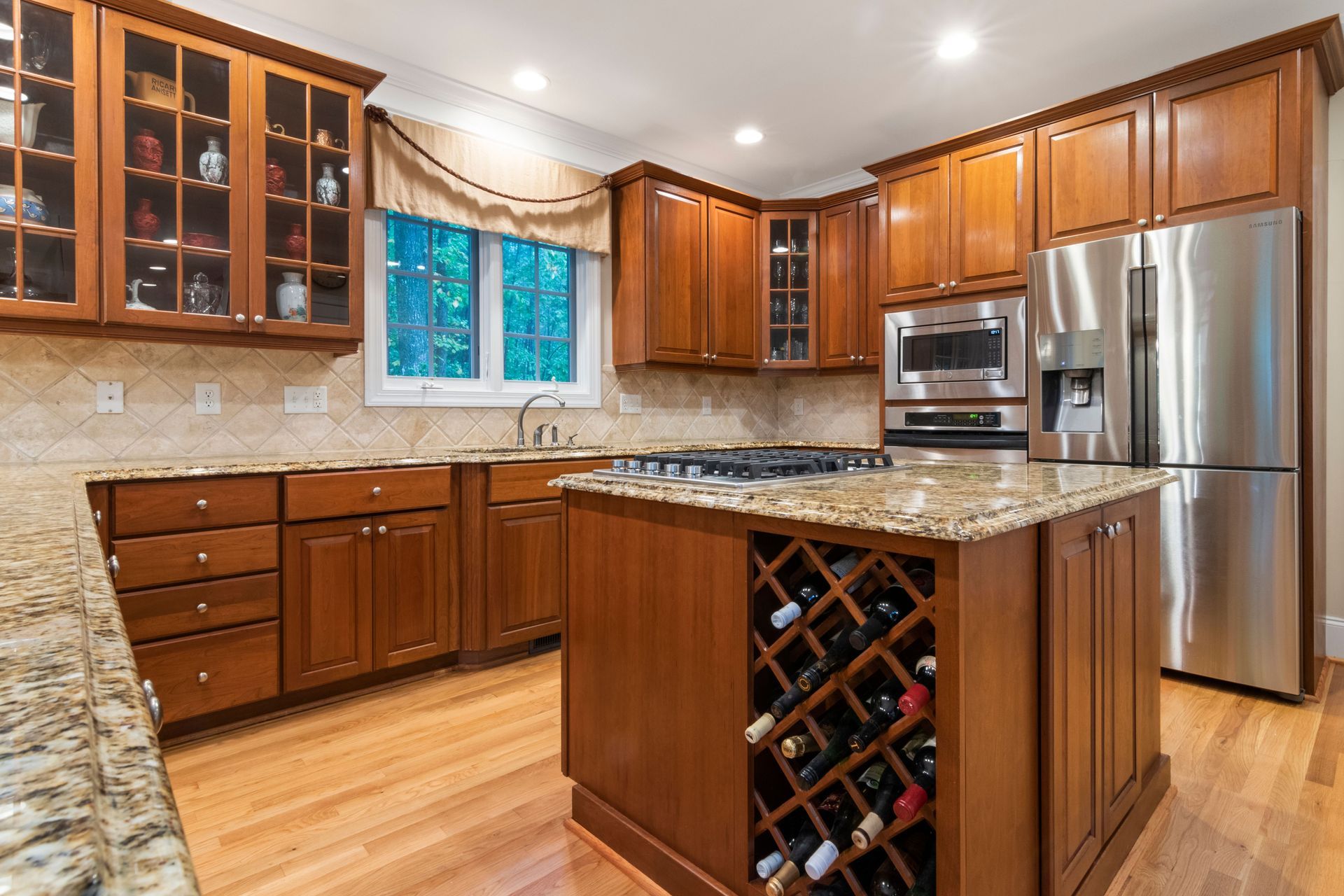 Modern kitchen with wooden cabinets, granite counters, stainless sappliances, and a wine rack island