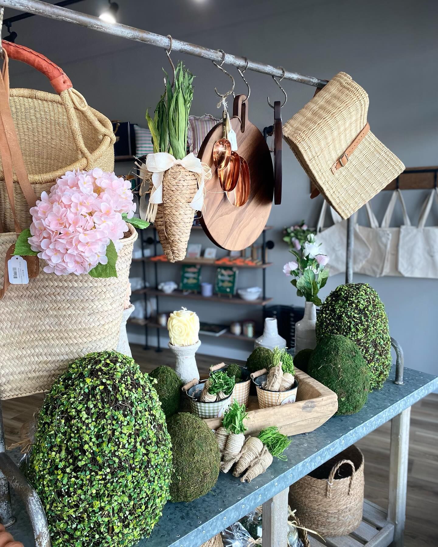 Display of woven bags, artificial plants, and decorative items on a store shelf.
