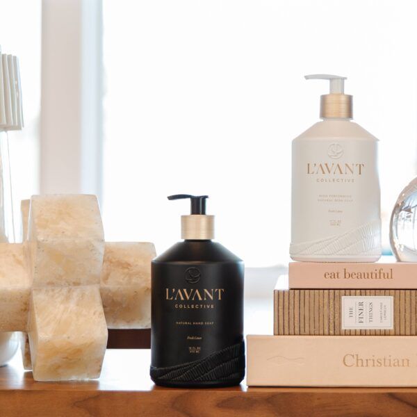 Black and white soap dispensers with gold accents, books, and decorative objects on a wooden surface.