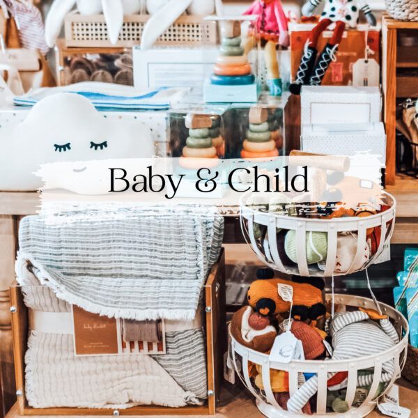 Display of baby and child items in a store, including blankets, toys, and a cloud-shaped pillow.