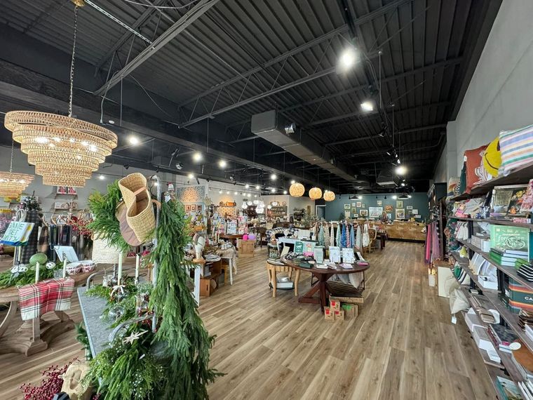Interior view of a well-lit gift shop with wooden floors, displays, and decorative chandeliers.