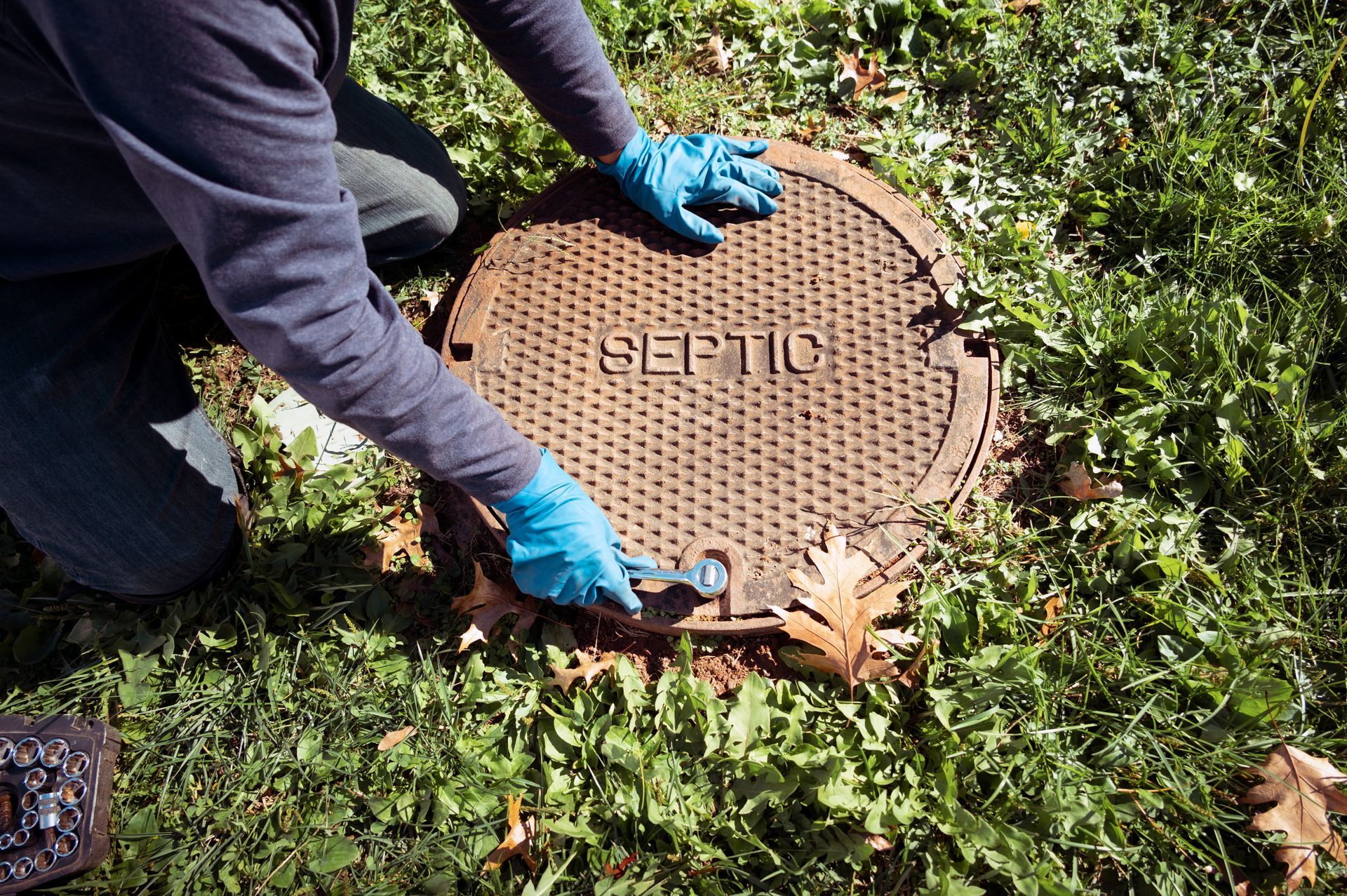 A working plumber opening septic system tank. A working plumber opening septic system tank.