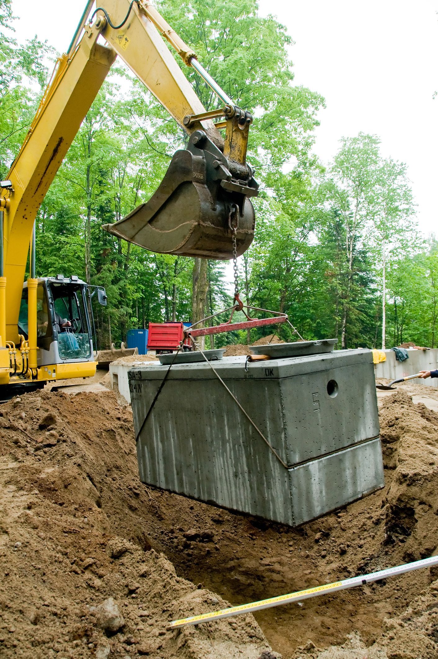 A man in blue pants engaged in a septic tank inspection, emphasizing the need for routine checks.