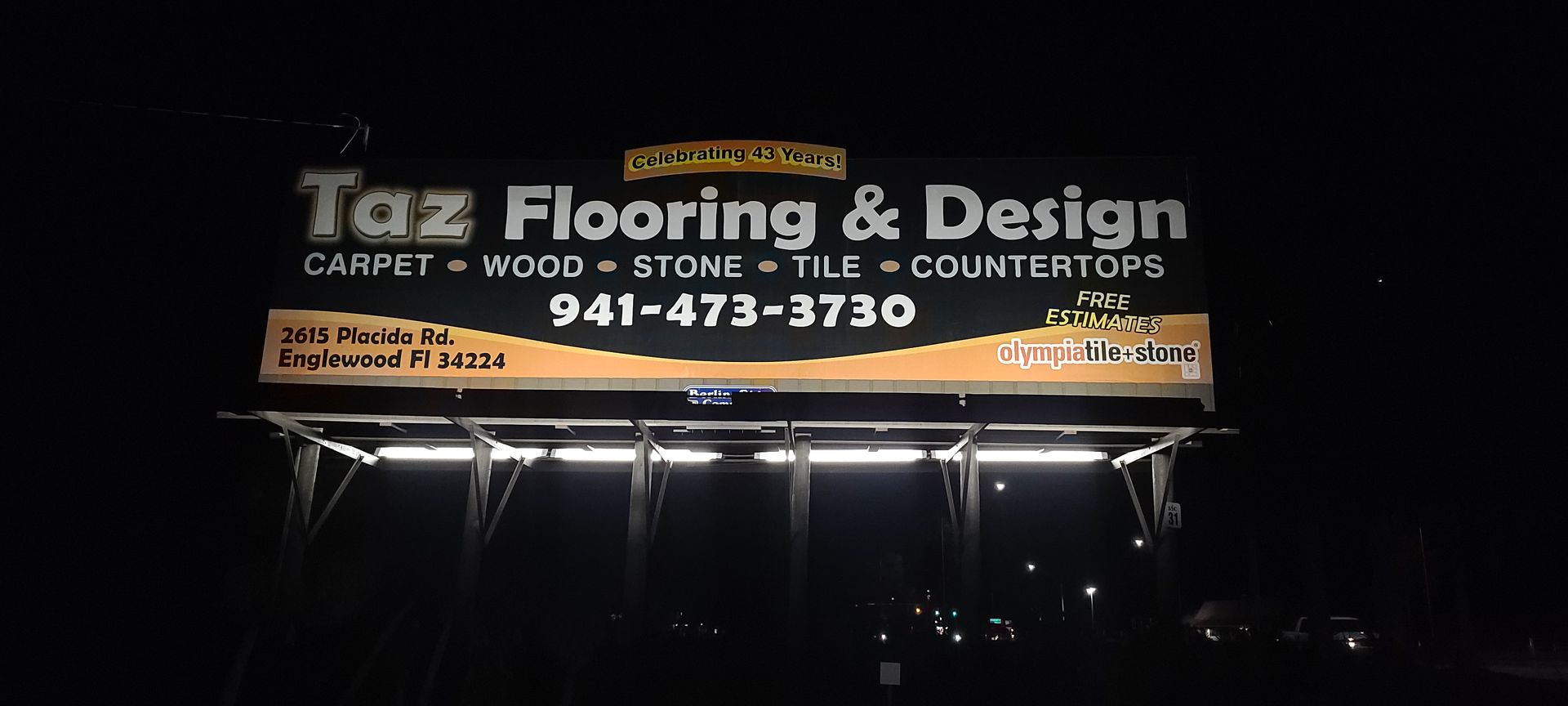 A billboard for tax flooring and design is lit up at night