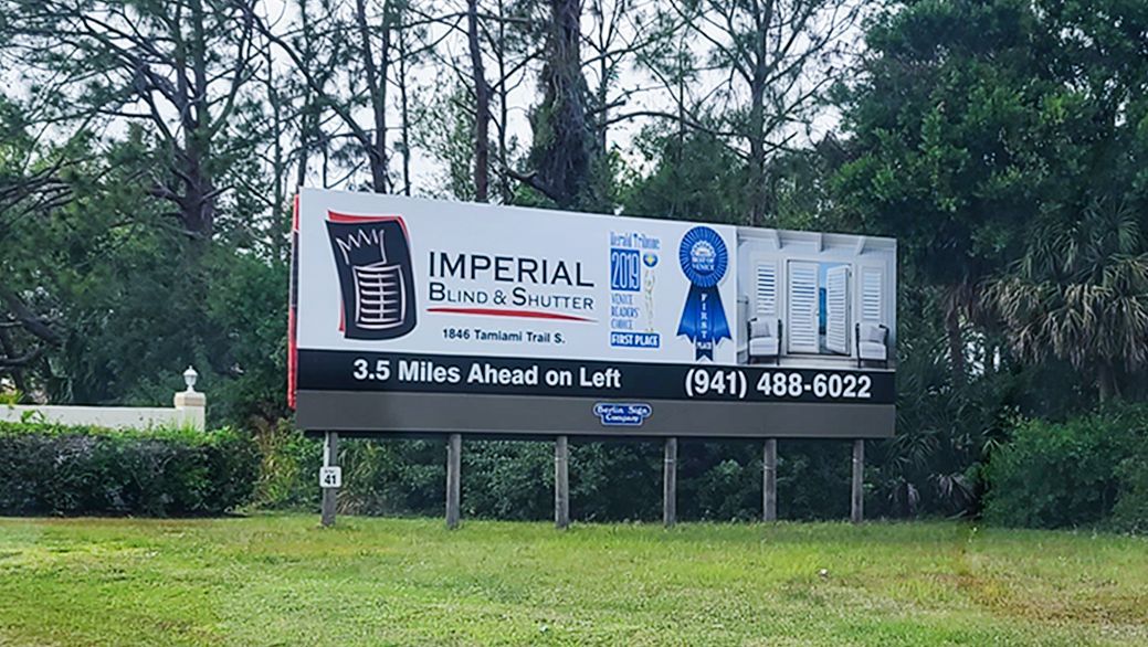 A large billboard is sitting in the middle of a grassy field.