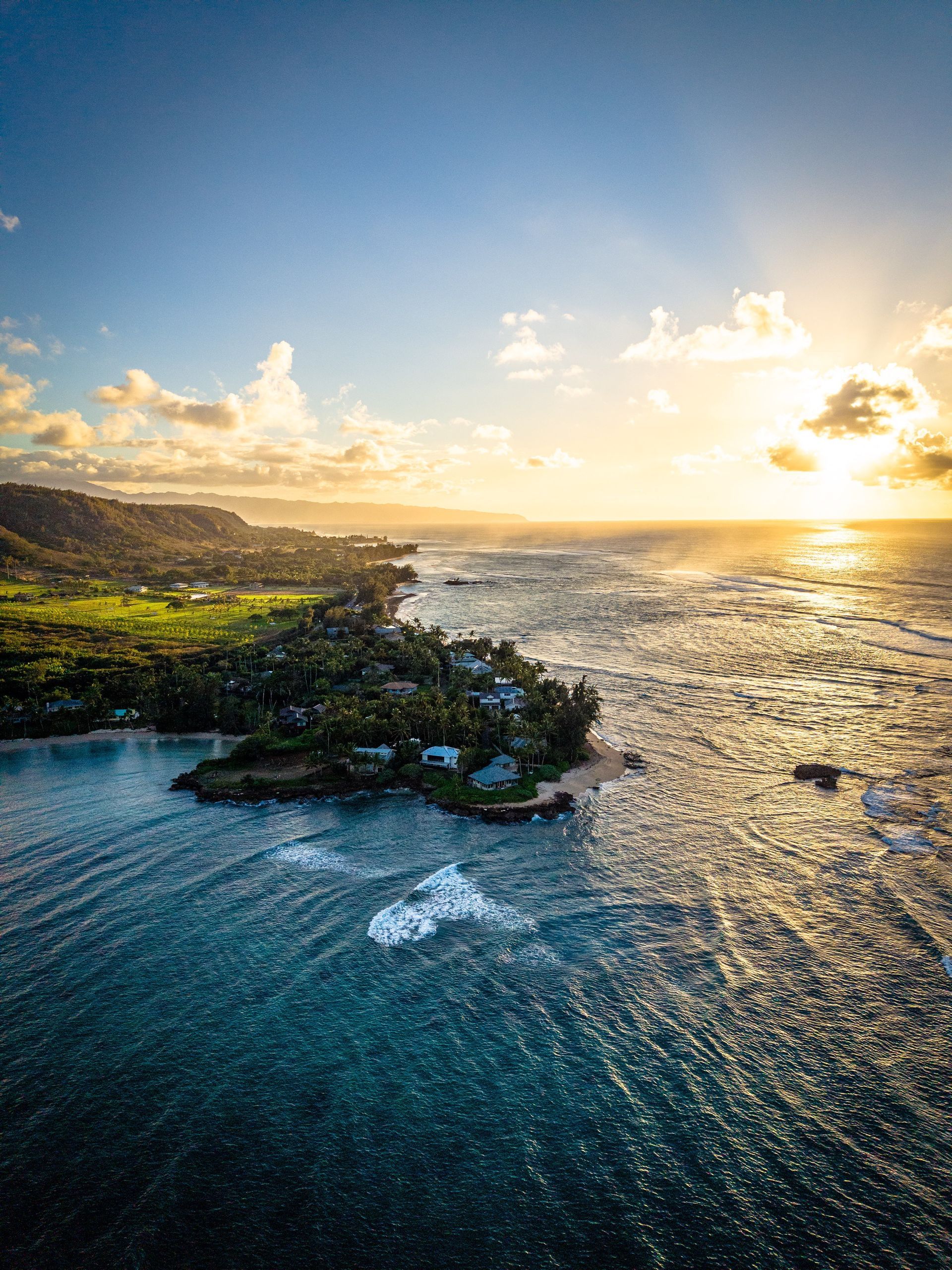 Ocean coastline at sunset, with waves crashing on shore and golden sunlight.