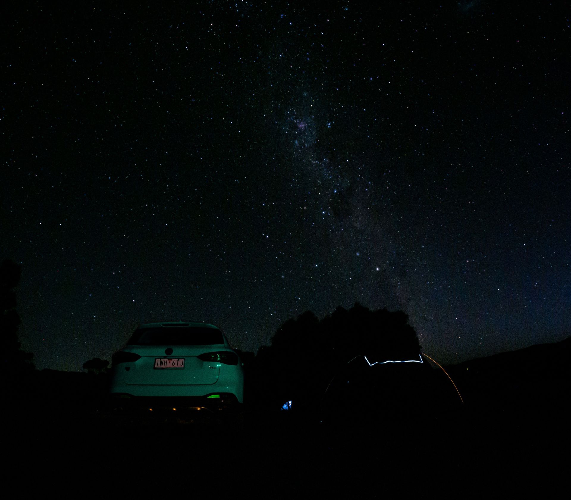 Car under a starry night sky, with the Milky Way visible.