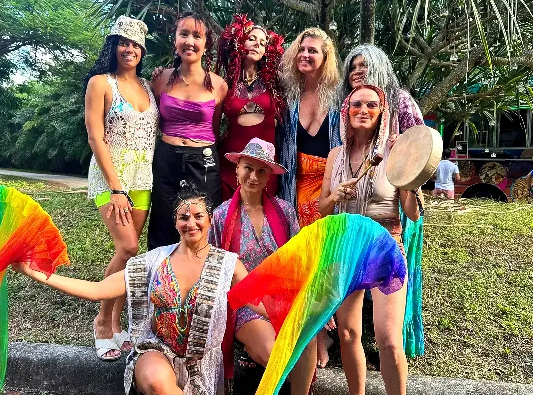 A group of women are posing for a picture while holding rainbow fans.