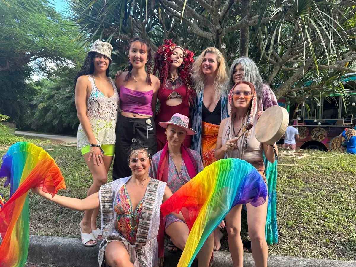A group of women are posing for a picture while holding rainbow fans.