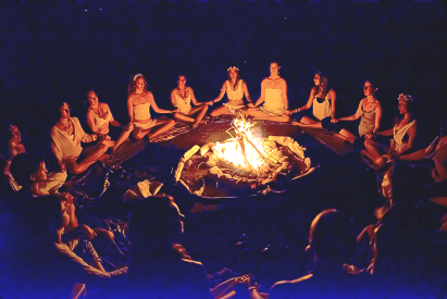 A group of people are sitting around a fire at night.
