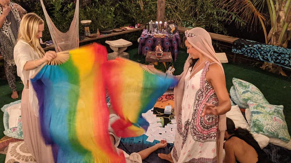 A group of women are standing around a rainbow flag.