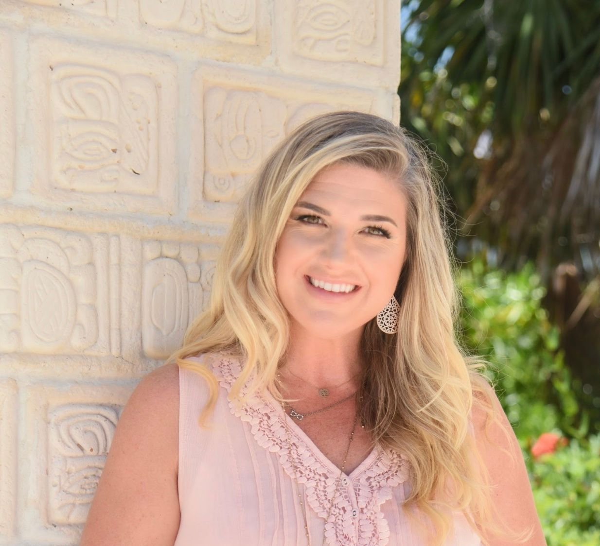 A woman is standing in front of a brick wall and smiling.