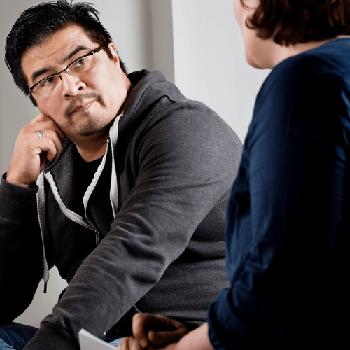 a man wearing glasses is talking to a woman