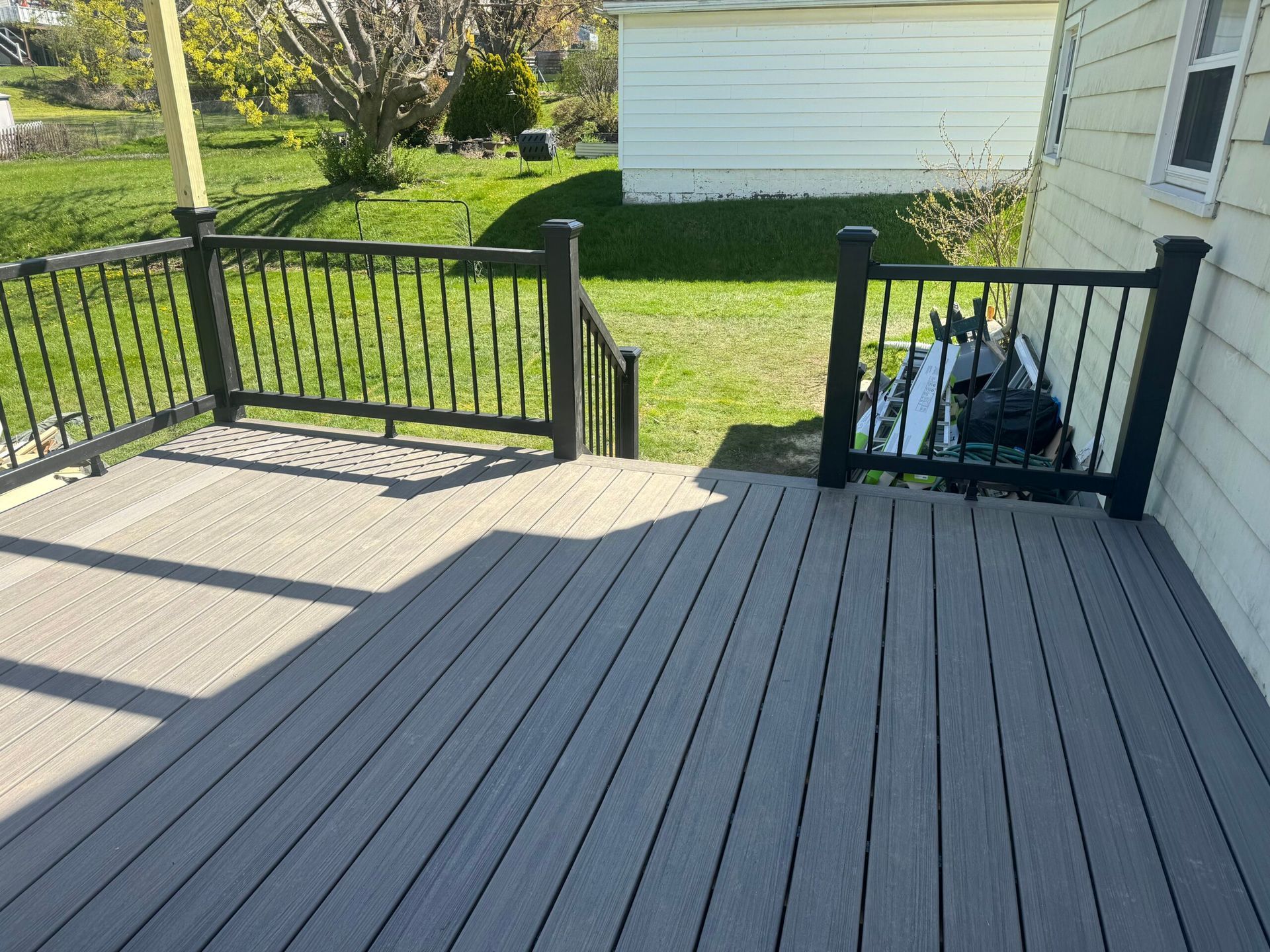 Gray composite deck with black railing and steps leading to a grassy yard.
