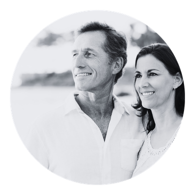 Smiling couple in white clothing outdoors, shown in a circular black-and-white portrait