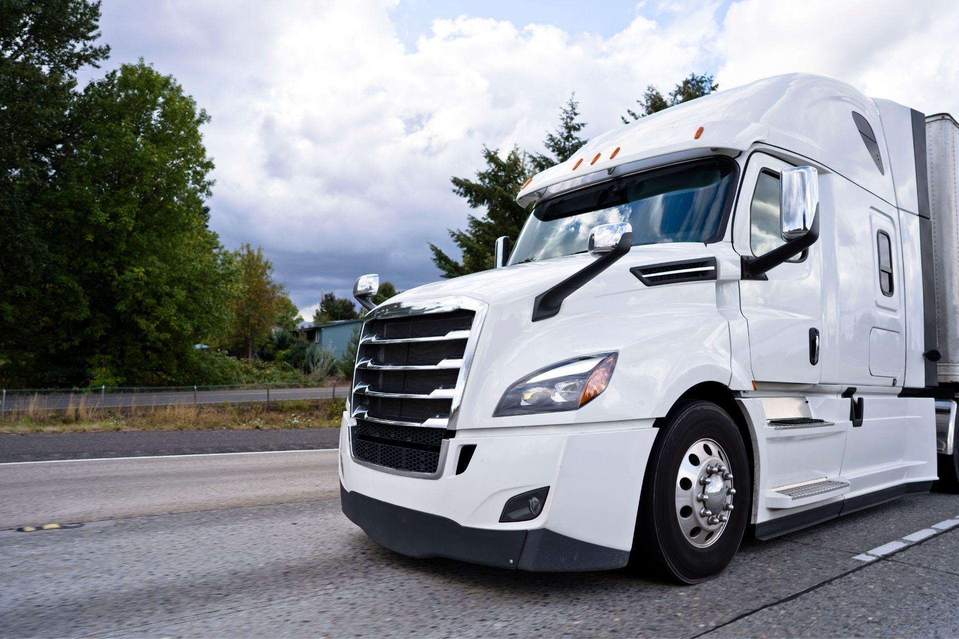 A white semi truck is driving down a highway.