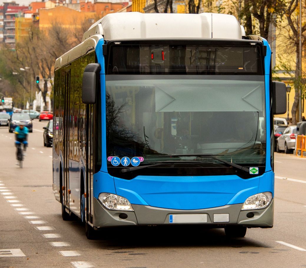 A blue bus is driving down a city street.