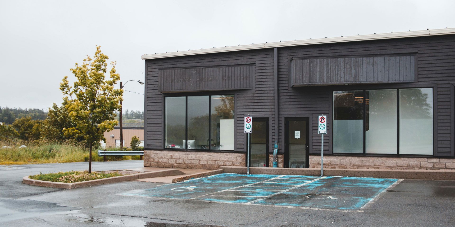 Storefront with two large windows and an accessible parking space marked in blue in front.