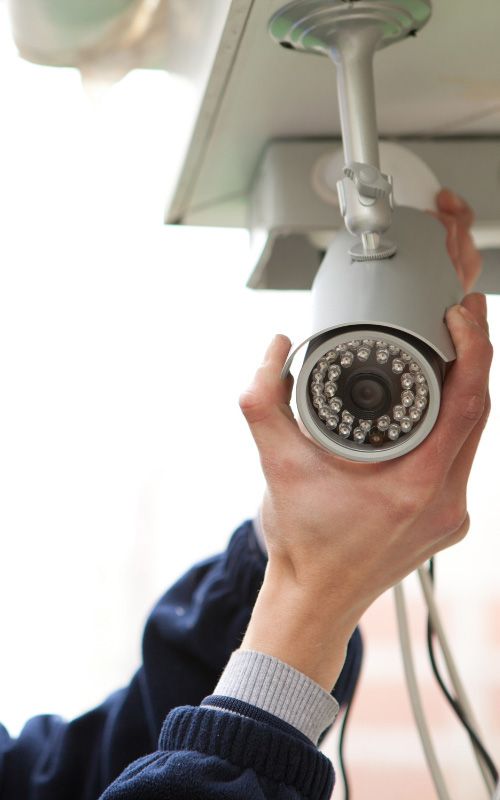Hands adjusting a ceiling-mounted security camera indoors
