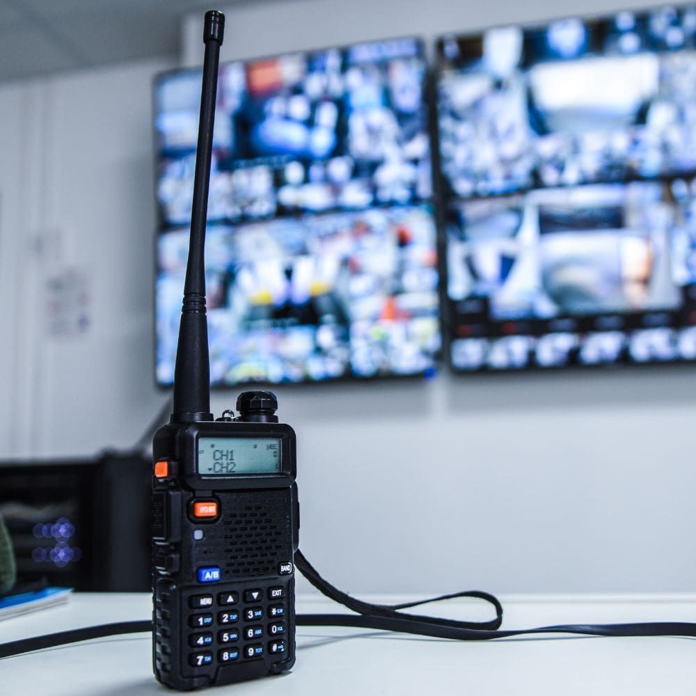A walkie talkie is sitting on a table in front of a security camera.