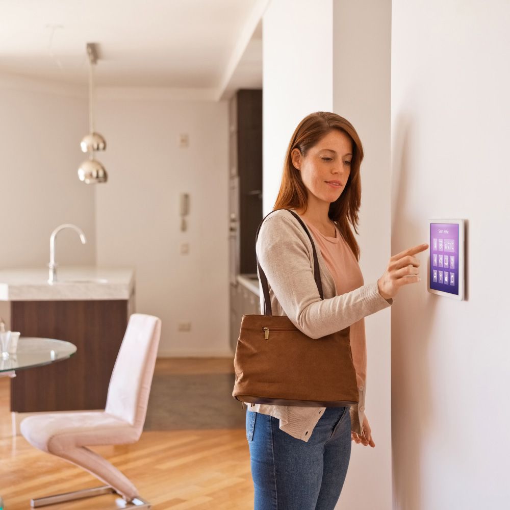 Woman using a wall-mounted touchscreen in a bright modern home interior