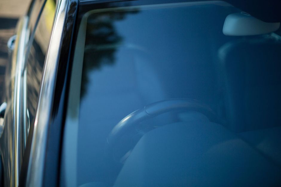 Primer plano del parabrisas de un coche azul, con reflejos y el volante visible en el interior