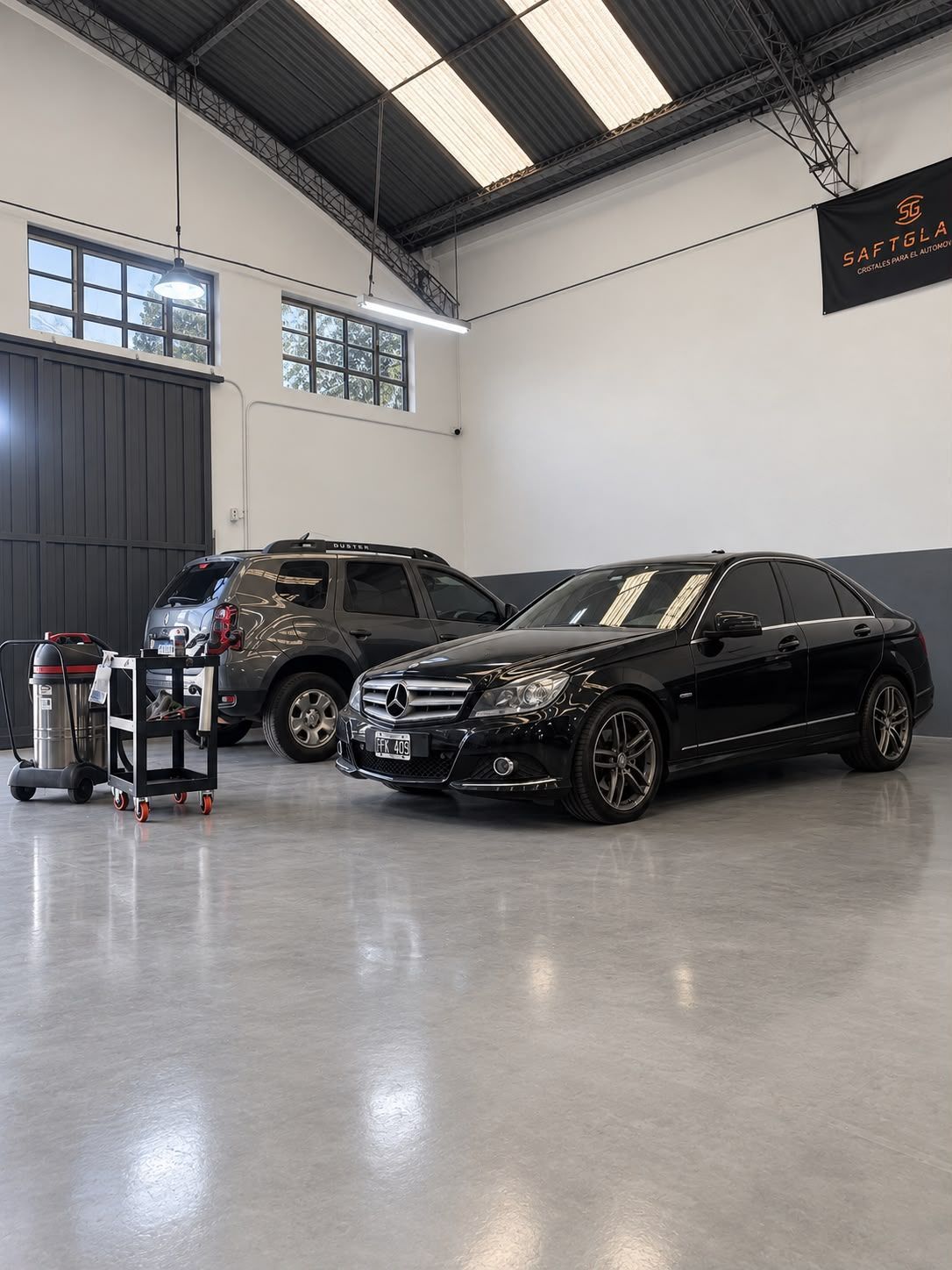 SUV Mercedes negro en un garaje impecable, junto a otro SUV y equipo de detailing