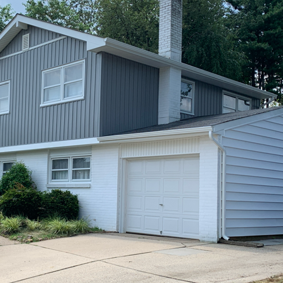 A gray and white house with a white garage door
