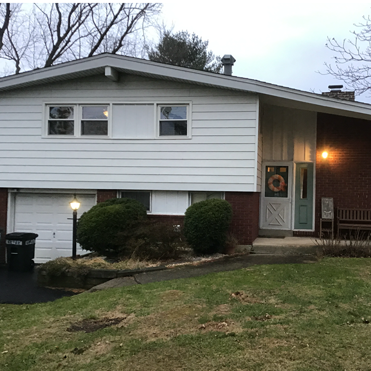 A brick house with a white siding and a blue door