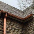 a close up of a copper gutter on the side of a brick building .