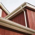 a red barn with a white gutter on the side of it .