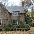 a large brick house with a lot of windows is surrounded by trees and leaves .