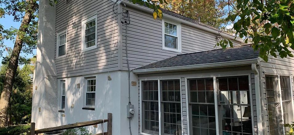 a white house with a screened in porch and lots of windows .