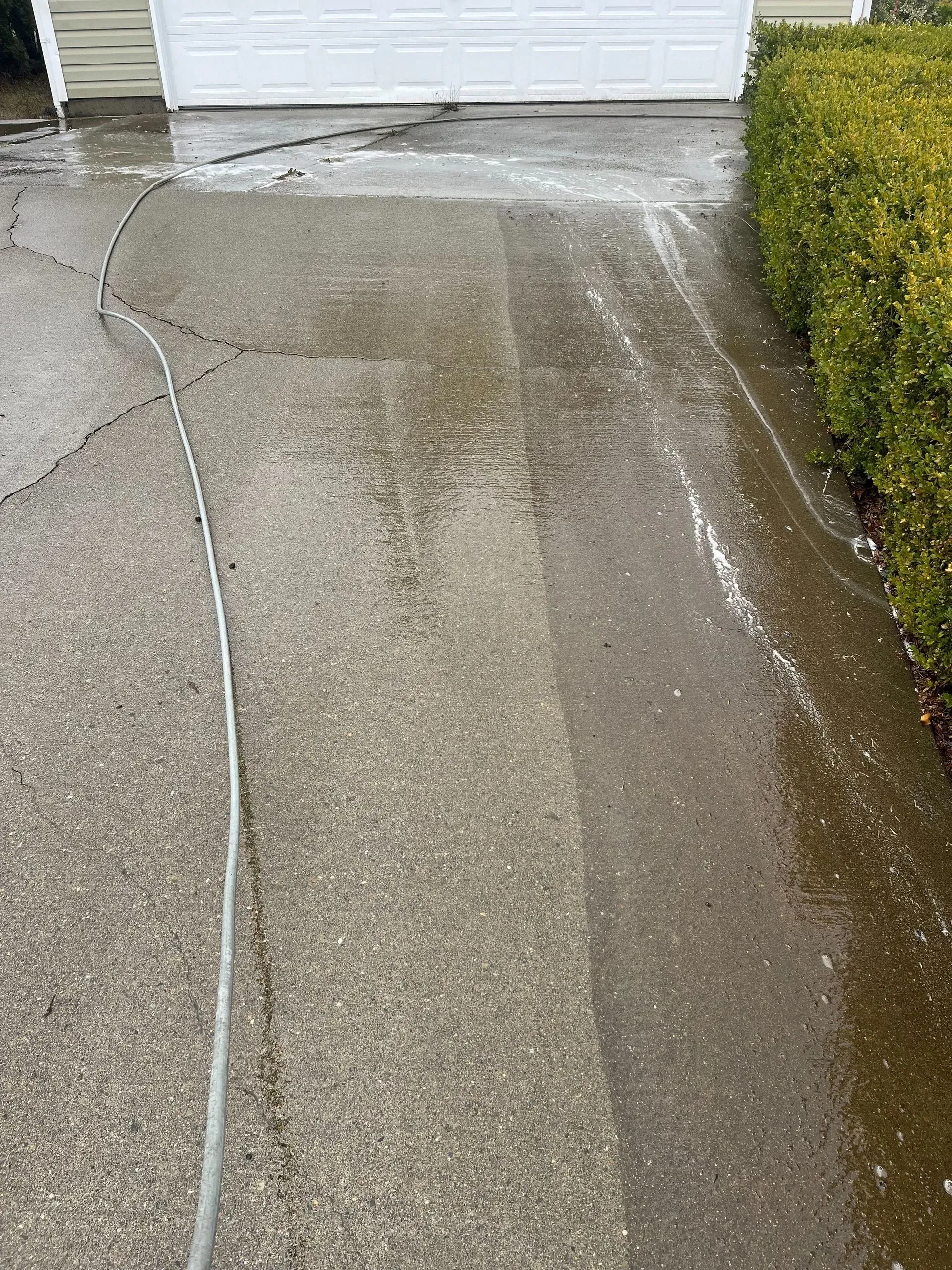 A concrete driveway is being cleaned with a pressure washer.