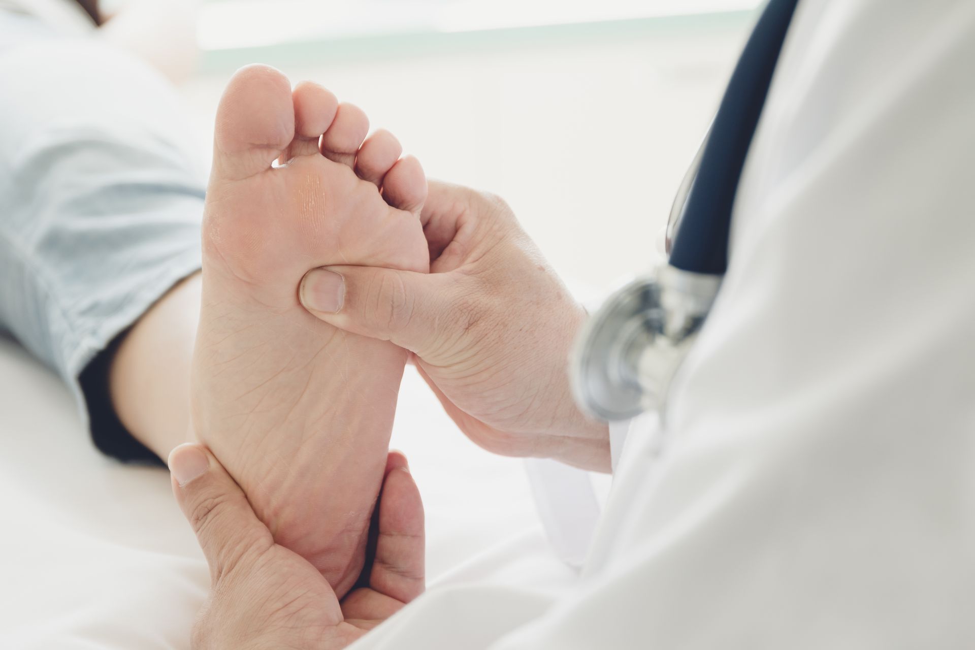 A medical professional examining the sole of a patient’s foot during a checkup in a bright clinic