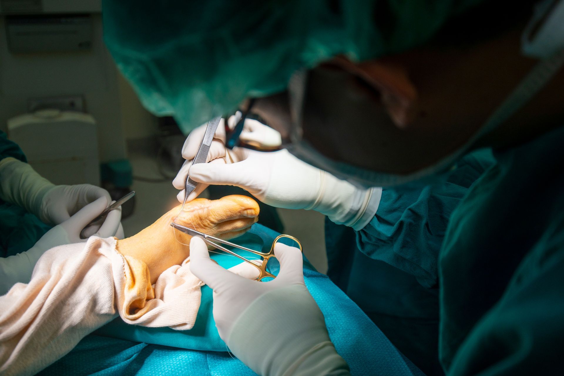 Surgeons performing foot surgery using sterile instruments under bright operating room lights
