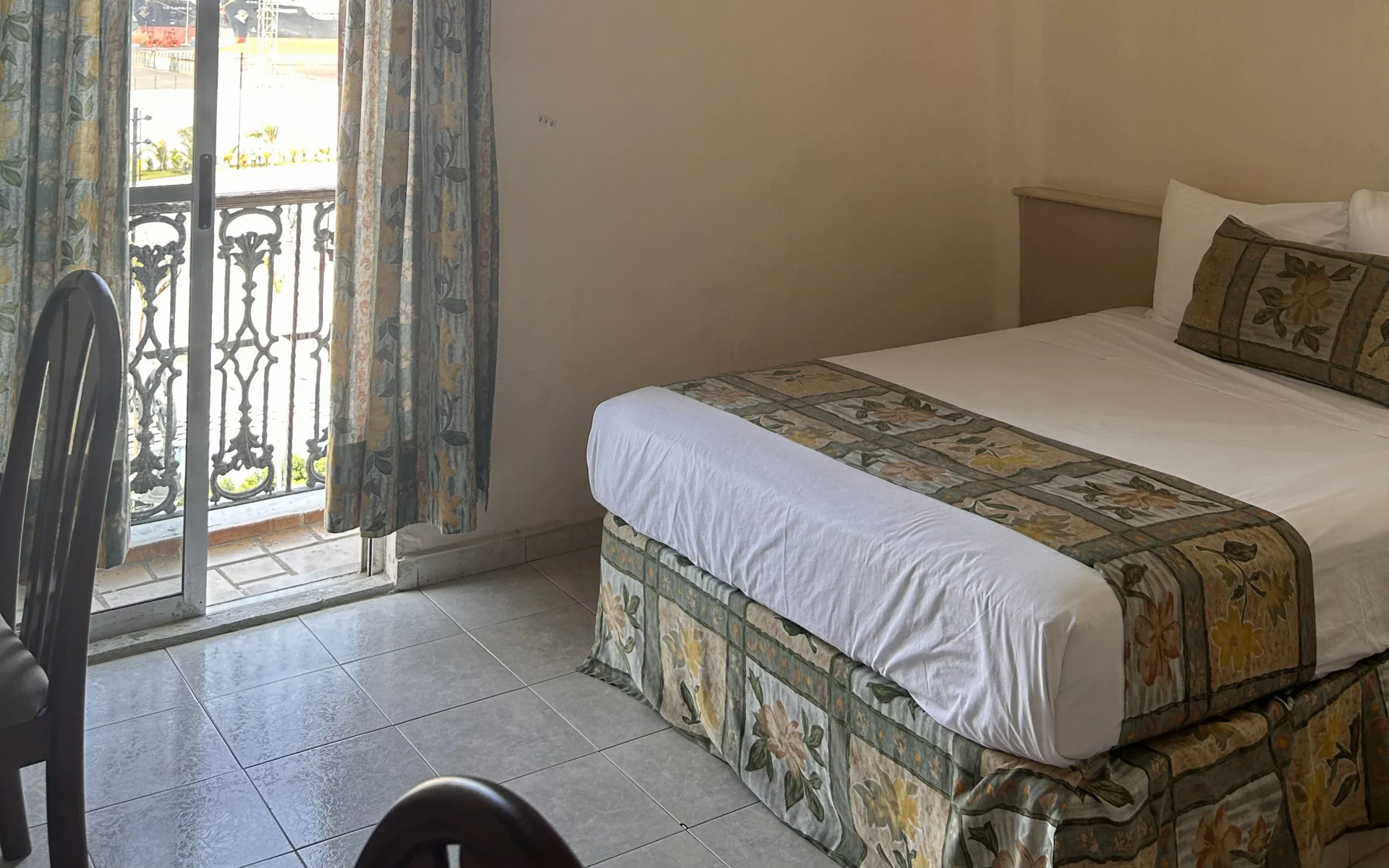 Un dormitorio con una cama de matrimonio con faldón y camino de cama estampados.